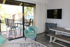 een woonkamer met een balkon met een tafel en stoelen bij Papakea Resort G406 in Lahaina