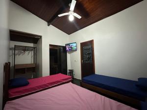 a bedroom with two beds and a ceiling fan at TRIPLEX piscina churrasqueira lava e seca Wi-Fi e 2 TVs em Condomínio com 90m2 no centro de Ubatuba in Ubatuba