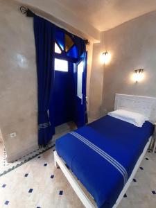 Cama azul en habitación con puerta azul en Dar Al Bahar, en Essaouira