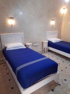 two beds in a room with blue sheets and pillows at Dar Al Bahar in Essaouira