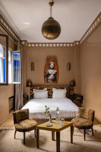 - une chambre avec un lit, une table et des chaises dans l'établissement Riad Goloboy, à Marrakech