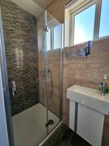 La salle de bains est pourvue d'une douche et d'un lavabo. dans l'établissement Marsaskala Sea View Duplex Penthouse - Mive Properties, à Marsaskala