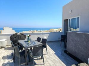d'une terrasse avec une table et des chaises sur un balcon. dans l'établissement Marsaskala Sea View Duplex Penthouse - Mive Properties, à Marsaskala