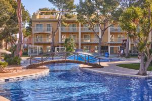 un puente sobre una piscina frente a un edificio en Zafiro Mallorca & Spa, en Can Picafort