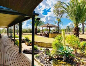 a patio with a pond and a umbrella and palm trees at Bella Farm Country House Hunter Valley in Nulkaba