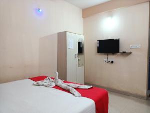 a bedroom with a bed with a red blanket and a tv at Bay Inn in Puri