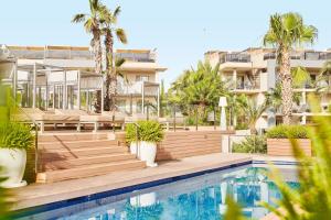 an apartment with a swimming pool and palm trees at Zafiro Palace Alcudia in Port d'Alcudia