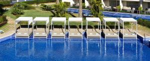 uma piscina com cadeiras e guarda-sóis num resort em Zafiro Palace Palmanova em Palmanova