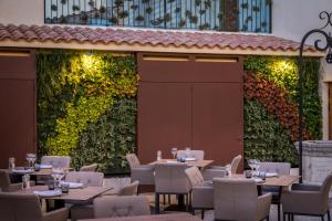a restaurant with tables and chairs in front of a green wall at Can Ribera by Zafiro in Muro