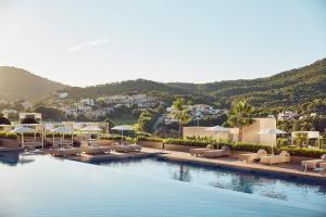 a pool with lounge chairs and umbrellas in a resort at Zafiro Palace Andratx in Camp de Mar