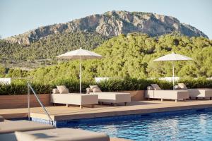 a pool with lounge chairs and umbrellas next to a mountain at Zafiro Palace Andratx in Camp de Mar
