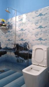a toilet in a bathroom with a mural of clouds at Holly House Homestay in Ella