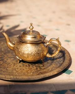 een antieke gouden theeketel op een bord bij Riad Rafaele & SPA in Marrakesh