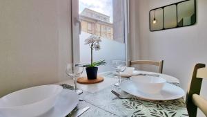 een eettafel met witte borden en wijnglazen bij La Résidence Évasion 2 - Original - Gare - Wifi - Relax BNB in Mulhouse