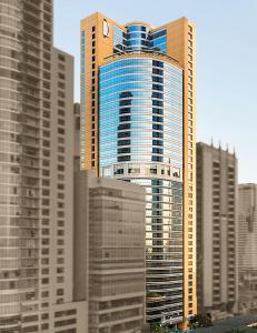 马尼拉Discovery Suites Manila, Philippines的一座高大的建筑,有蓝色的窗户,位于城市