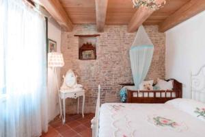 1 dormitorio con cama y pared de ladrillo en Appartamento in centro storico, en San Giovanni in Marignano