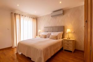 a bedroom with a large white bed with a window at Miradouro da Penha in Faro