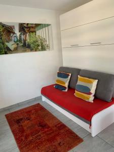 una habitación con un sofá rojo con almohadas y una pintura en Altéa, en Pessac