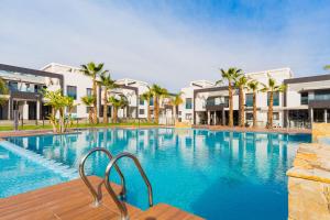 uma grande piscina com palmeiras e edifícios em ALEGRIA ID30 em Playa Flamenca