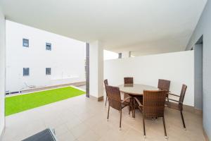 a dining room with a table and chairs and a green lawn at ALEGRIA ID30 in Playa Flamenca