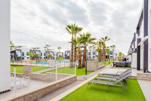 un balcon avec bancs, palmiers et bâtiments dans l'établissement ALEGRIA ID30, à Playa Flamenca