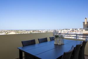 a blue table and chairs on a balcony with a view at Miradouro da Penha in Faro