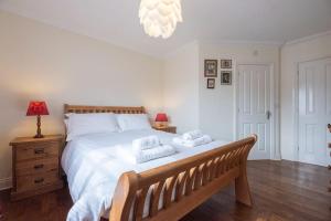 a bedroom with a large white bed with a bench at The Little Hopton, Saxmundham in Saxmundham