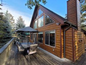 レイディアム・ホット・スプリングスにあるPine Cone Cabin by StayInのデッキにテーブルと椅子が備わるキャビン