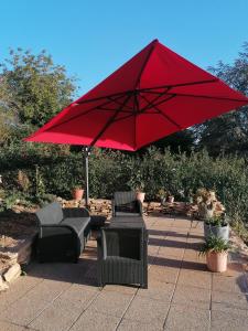 einen roten Regenschirm auf einer Terrasse mit Stühlen in der Unterkunft Pour une halte aux portes de Bourgoin 
