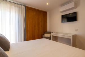 - une chambre avec un lit et une télévision murale dans l'établissement Miradouro da Penha, à Faro