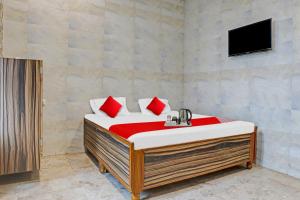 - une chambre avec un lit doté d'oreillers rouges et une télévision dans l'établissement Flagship New Mansi Hotel, à Bilāspur