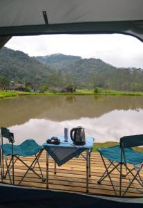 a table and chairs on a deck next to a lake at Recanto do Vale Glamping in Pomerode