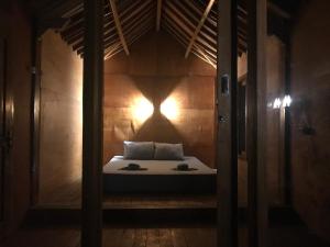 a room with a bed with a light on the wall at Muni's Lombok Bungalow in Masbagik