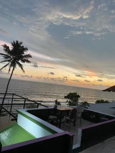 a patio with a table and a palm tree and the ocean at Pupa Homestay &Surf school in Trivandrum