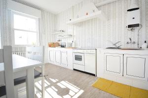 a kitchen with white cabinets and a table and a window at GALIHOST - A Casa do Patio in Vilagarcia de Arousa