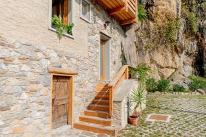 a stone house with a wooden door and stairs at Green Chalet Scalotta - Private Garden with Pool in Dervio