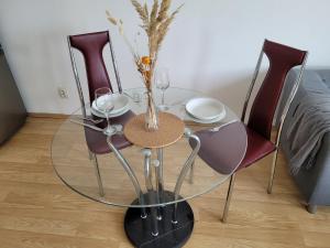 a glass table with three chairs and wine glasses at Apartmán Neva Sereď in Seredʼ