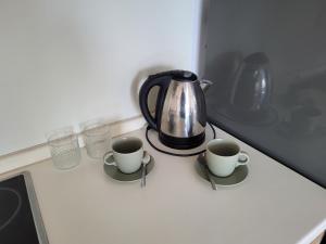 a tea kettle and two cups on a counter at Apartmán Neva Sereď in Seredʼ
