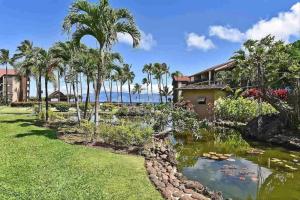 een huis met een vijver en palmbomen bij Papakea Resort G406 in Lahaina