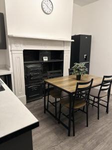 a dining room with a table and chairs and a clock at 5-Bed Apartment in Altrincham near airport in Altrincham