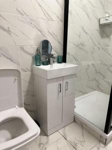 W łazience znajduje się umywalka, toaleta i lustro. w obiekcie 5-Bed Apartment in Altrincham near airport w mieście Altrincham