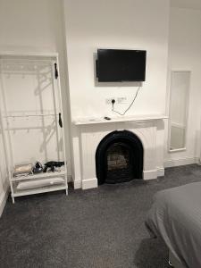 Habitación con chimenea y TV en la pared. en 5-Bed Apartment in Altrincham near airport, en Altrincham