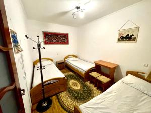 a small room with two beds and a table at Sunny Valley Karakol in Karakol