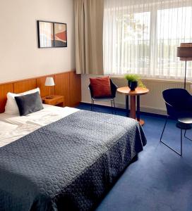 a hotel room with a bed and two chairs and a table at Garni Hotel Gartenstadt Erfurt in Erfurt