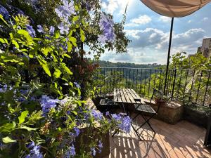 eine Terrasse mit einem Tisch und lila Blumen in der Unterkunft Terrazza sul Tufo in Pitigliano