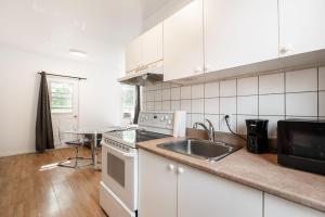 a kitchen with white cabinets and a sink and a table at Appartement 1 chambre 1 lit queen-1009 in Montreal