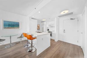 a kitchen with white cabinets and a table and chairs at Modern 1-BD Arya Condo - Coconut Grove w-Pool & Parking in Miami