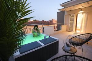 una donna seduta in una vasca idromassaggio sul balcone di Hotel Cenisio a Rimini