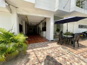 patio con tavolo, sedie e ombrellone di HOTEL LIGHT PLAZA a Aguachica