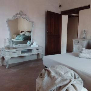 1 dormitorio con cama blanca y espejo en B&B Casale Ormano, en San Venanzo